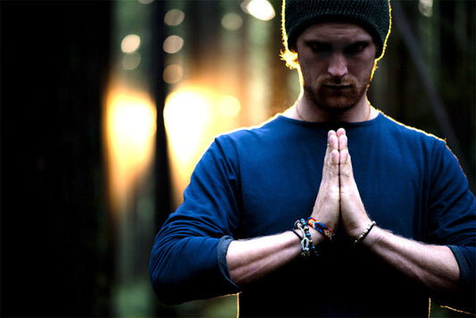 Man with hands in prayer in a shirt by eco clothing company Movement Global. 